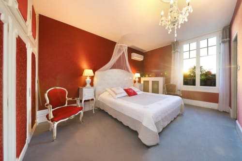 Chambre rouge luxueuse au Château de Quesmy B&B avec vue sur le jardin, lit blanc, lustre et mobilier classique