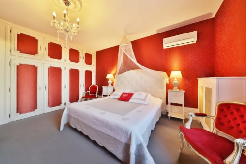Chambre luxueuse rouge au Château de Quesmy avec lit blanc, lustre en cristal et décor français classique