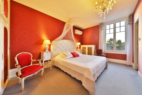 Chambre rouge luxueuse au Château de Quesmy avec lit à baldaquin, vue sur le jardin et décoration élégante