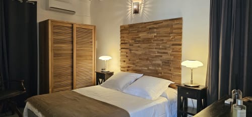 Charmantes Bungalow-Schlafzimmer in der Habitation Villa Les Cassias mit Holzkopfteil, blauen Kissen und zeitgenössischer Beleuchtung