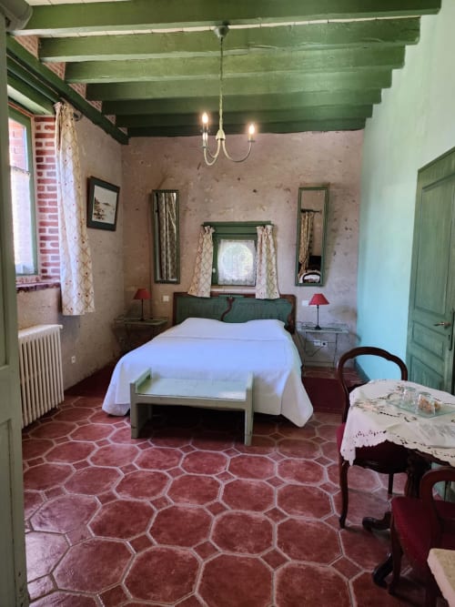 Chambre 1 du Manoir De La Maison Blanche à Amboise avec plafond à poutres vertes, lit blanc et sol en carreaux de terre cuite