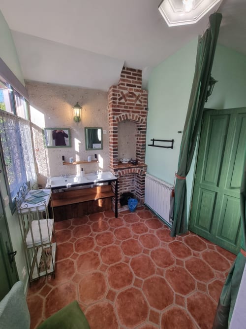Camera spaziosa al Manoir De La Maison Blanche ad Amboise con camino in mattoni, toletta in legno, pavimento in cotto e dettagli verdi