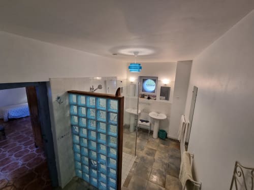 Modern bathroom in Amboise hotel with blue glass block shower partition and white fixtures