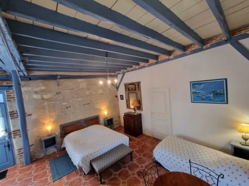 Spacious bedroom at Manoir De La Maison Blanche in Amboise with two beds, exposed beams, brick walls, and garden view artwork