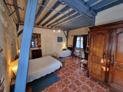 Chambre spacieuse au Manoir De La Maison Blanche à Amboise avec poutres en bois bleu, deux lits, armoire en bois et teintes terracotta