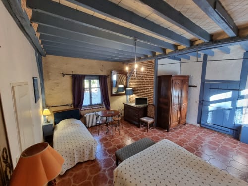 Spacious bedroom at Manoir De La Maison Blanche in Amboise with exposed beams, brick walls, twin beds, and garden views
