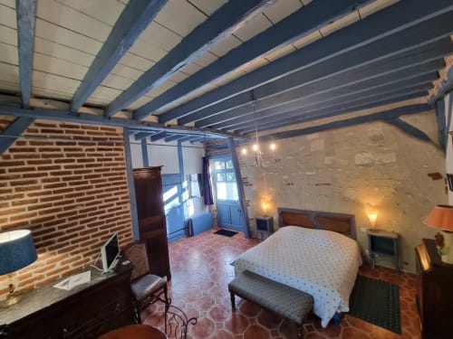 Rustic bedroom with exposed brick, wooden beams, bed, desk and warm lighting at Manoir De La Maison Blanche in Amboise