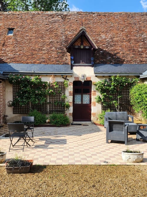 Charming brick courtyard at Manoir De La Maison Blanche in Amboise with ivy-covered walls, wooden door, and garden seating
