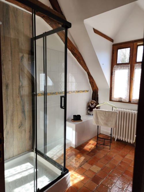 Bagno moderno con doccia walk-in, piastrelle in cotto, travi in legno e finestre con vista sul giardino presso Manoir De La Maison Blanche