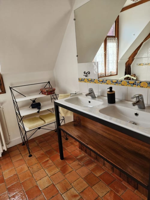 Bagno rustico con doppi lavabi, mobile in legno, piastrelle in terracotta e soffitto mansardato del Manoir De La Maison Blanche, Amboise