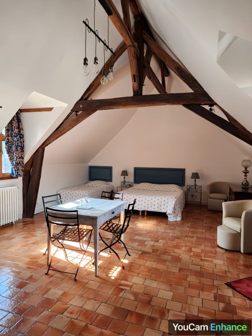 Spacieuse chambre mansardée avec poutres en bois apparent, deux lits, bureau et carrelage en terre cuite au Manoir De La Maison