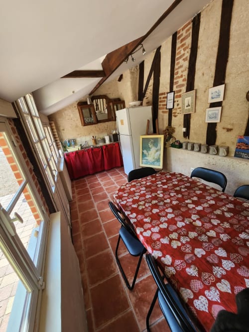Camera accogliente con copriletto rosso decorato, tavolo da pranzo, angolo cottura e travi a vista al Manoir De La Maison Blanche, Amboise