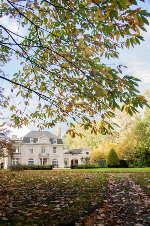 Castanea Business & Suites in Merelbeke framed by autumn foliage and falling leaves