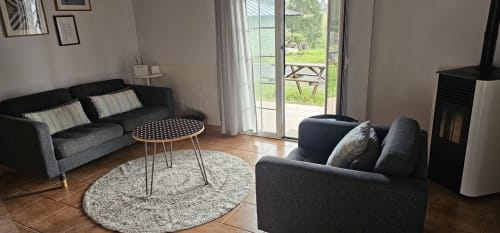 Salón moderno del dúplex Bizkar Bare en Vizcaya con sofás grises, chimenea y vistas a las montañas desde las puertas del patio