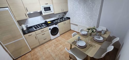 Moderna cocina-comedor en habitación dúplex Bizkar Bare, Vizcaya con muebles de madera, encimera negra y mesa preparada.