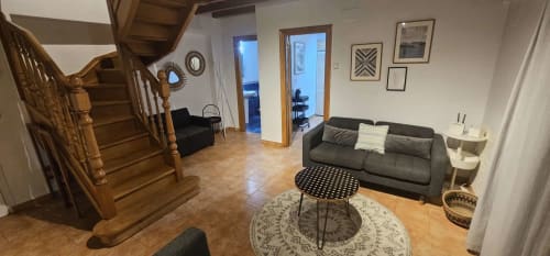 Moderno salón de dúplex en Bizkar Bare con escalera de madera, sofá gris, mesa redonda y vistas a la montaña en Vizcaya