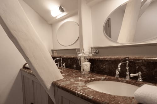 Elegant bathroom at Castanea Business & Suites with dark marble countertop, dual sinks, and circular mirrors in Merelbeke