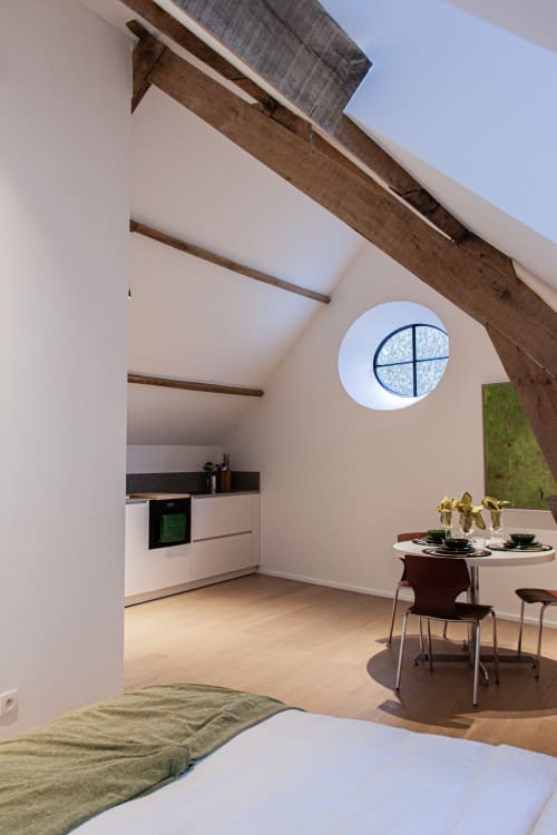 Modern studio at Castanea Business & Suites in Merelbeke with bed, kitchenette, dining area, and circular window