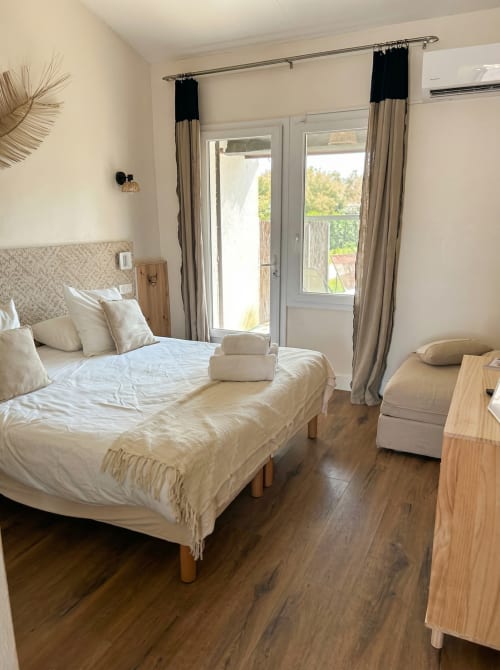 Bright triple bedroom at Hôtel du Pont Blanc with garden view, cream bedding, wood flooring, and glass doors opening to
