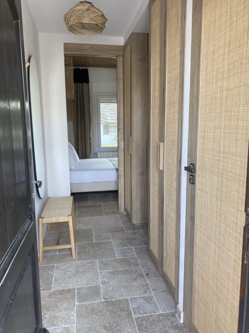 Modern hallway in Chambre Triple Supérieure at Hôtel du Pont Blanc, with wooden wardrobe, stone flooring, and bedroom view in