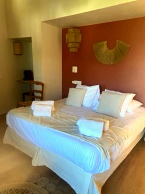 Elegant triple bedroom at Hôtel du Pont Blanc in Saintes-Maries-de-la-Mer with terracotta walls, white linens, and garden