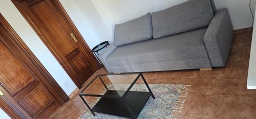Sala de estar moderna en Bizkar Bare Vizcaya con sofá gris, mesa de café negra y suelo de madera