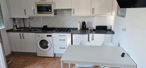 Cocina moderna en apartamento Bizkar Bare con muebles blancos, estufa de gas, lavadora y mesa de comedor