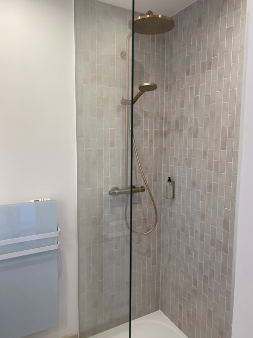 Modern shower enclosure at Hôtel du Pont Blanc with rainfall and handheld showerheads, grey subway tile walls