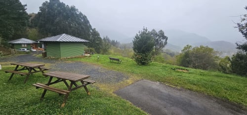 Jardines del apartamento Bizkar Bare en Vizcaya con mesas de picnic, césped verde y vistas a bosques de montaña