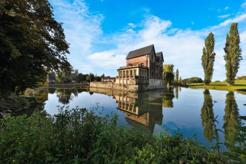 Château de Quesmy se reflétant dans une eau calme avec des peupliers, Quesmy, France