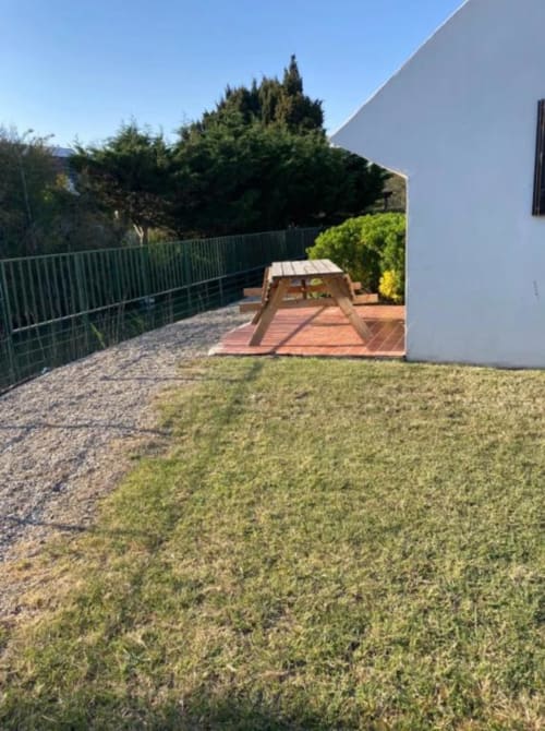 Maison de Gardian garden view at Hôtel du Pont Blanc with lawn, wooden deck, and cypress trees