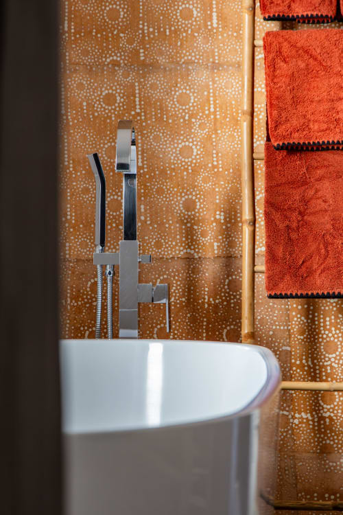 Modern bathroom detail at Villa Figue Blanche with white bathtub, chrome fixtures, and patterned wallpaper in
