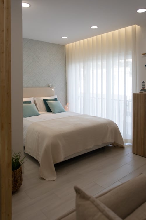 Dormitorio moderno del apartamento Casa Lumar en Sesimbra Sun Sea con cama queen, almohadas turquesas, cortinas blancas e iluminación empotrada