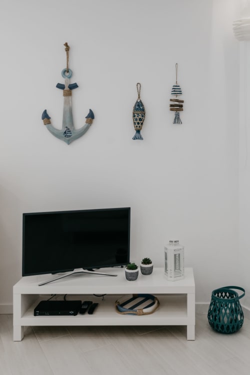 Sala de estar costera con televisor, consola blanca y decoración náutica en Sesimbra Sun Sea