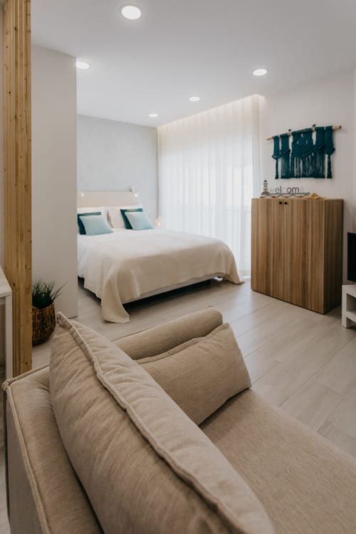 Dormitorio moderno en apartamento Casa Lumar de Sesimbra Sun Sea con cama queen, detalles en verde azulado, muebles de madera y diseño contemporáneo