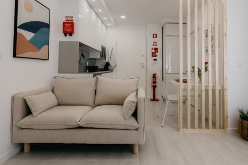 Sofá beige moderno en apartamento diáfano y luminoso en Sesimbra Sun Sea, con cocina, divisor de madera y arte contemporáneo