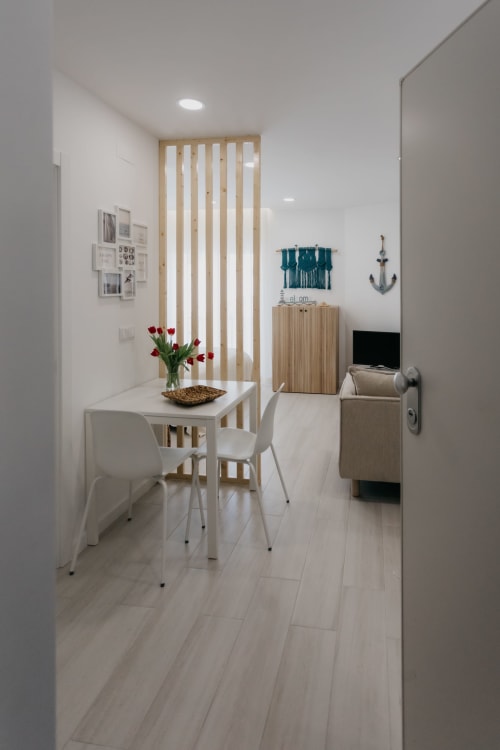 Comedor moderno con mesa blanca, divisor de madera, tulipanes rojos y decoración náutica en Sesimbra