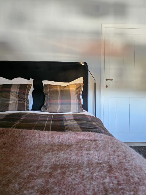 Cozy bedroom at Castanea Business & Suites in Merelbeke with plaid bedding, black headboard, and white wardrobe doors