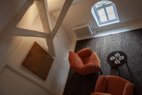 Thérèse Suite at Castanea Business & Suites in Merelbeke featuring orange armchairs, skylight, and modern decor