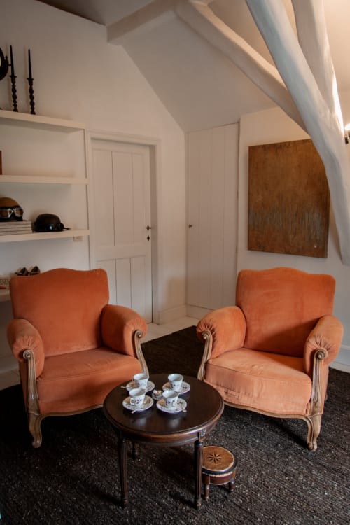 Elegant sitting area in Thérèse Suite at Castanea Business & Suites, Merelbeke, with two coral armchairs and dark round table