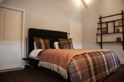 Thérèse Suite bedroom at Castanea Business & Suites in Merelbeke with plaid bedding and dark iron bed frame