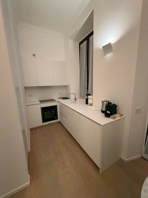 Modern white kitchen in Maisons Milano apartment with stainless steel appliances and wooden flooring