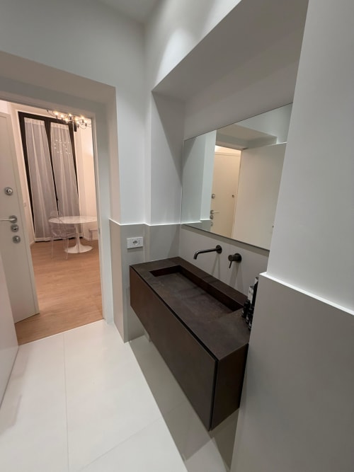 Modern bathroom at Maisons Milano with dark vanity, wall-mounted faucet, illuminated mirror, and access to bedroom