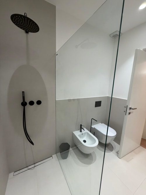 Modern bathroom at Maisons Milano with rainfall shower, black fixtures, toilet, and bidet in minimalist design