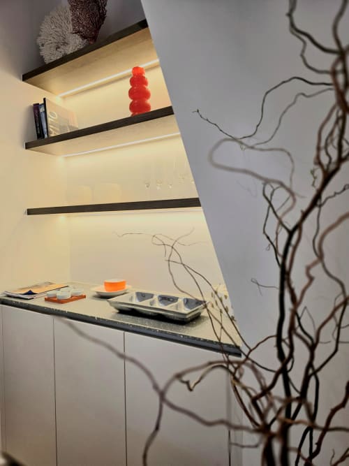Modern studio apartment at Castanea Business & Suites with illuminated shelving, decorative branches, and minimalist décor in