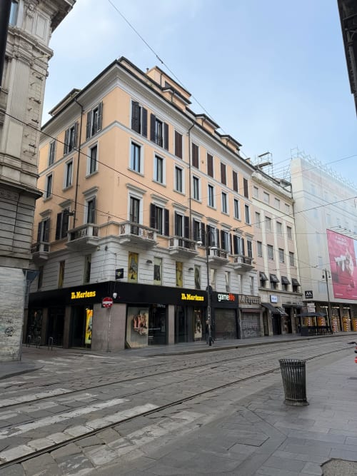Palazzo Maisons Milano in Via Dei Piatti nel centro di Milano con elegante facciata color pesca e negozi al piano terra