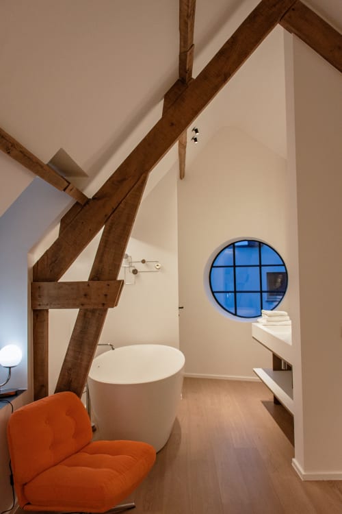 Modern bathroom in Studio Fabienne at Castanea Business & Suites with exposed wooden beams, circular window, and round white