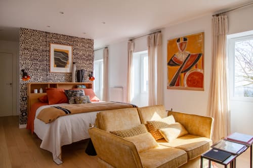 Stylish bedroom at Villa Figue Blanche B&B in Montagny-les-Buxy with orange accents, modern artwork, and comfortable seating
