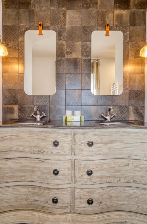 Luxury dual vanity bathroom at Villa Figue Blanche with rounded mirrors, wood cabinetry and ornate tile backsplash,