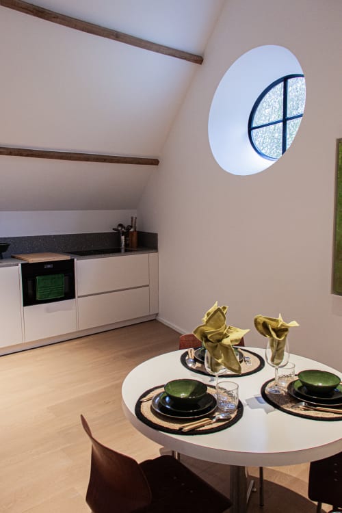 Studio Catherine at Castanea Business & Suites in Merelbeke features a round dining table with place settings, modern